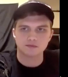 Photo of Liam MacNeil that is a close up of his face, he is in a black t-shirt and baseball cap. 