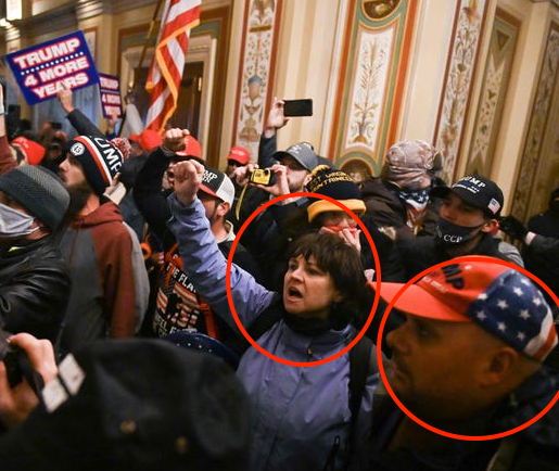 Sue Ianni and Mark Sahady in the Capitol building. Sue's fist is raised in the air. There are other Trump supporters crowded around them. Two hold signs that say "Trump 4 More Years."