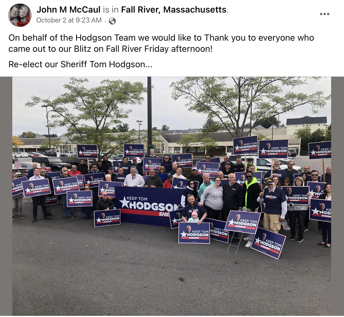 Facebook post from John McCaul: "John M McCaul is in Fall River, Massachusetts. October 2 at 9:23 AM. On behalf of the Hodgson Team we would like to Thank you to everyone who came out to our Blitz on Fall River Friday afternoon! Re-elect our Sheriff Tom Hodgson..." Below the text is an image of around 40 people in a parking lot holding large "Keep Tom Hodgson Sheriff" signs. John McCaul is in the front of the crowd in a white shirt.